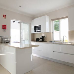 Brand new modern kitchen with white cabinets and beige stone counter top and ceramic tiled floor